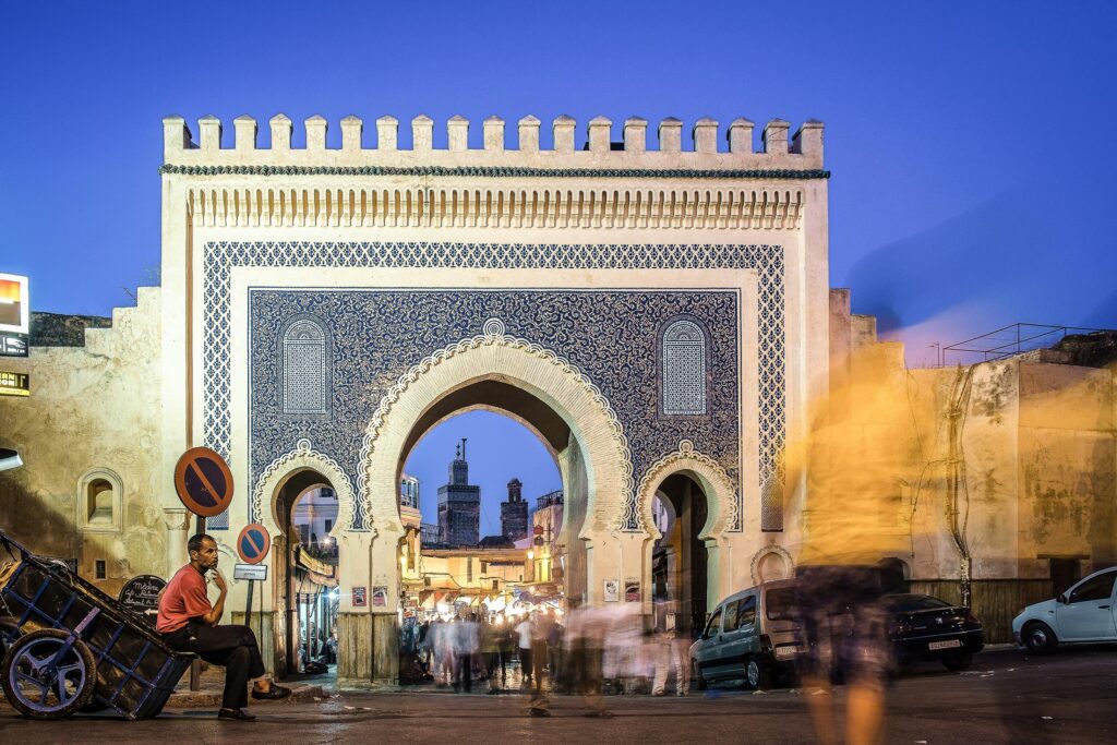 The ornate Bab Bou Jeloud gate in Fez, Morocco, illuminated at dusk.