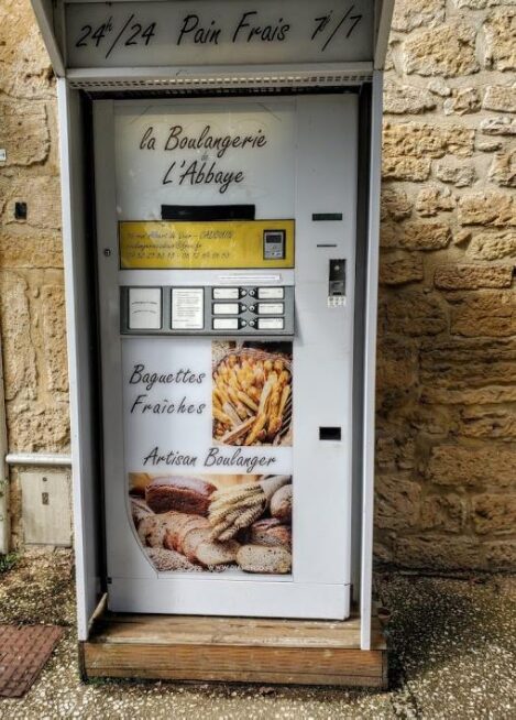 Vending machine selling fresh baguettes in a rustic setting.