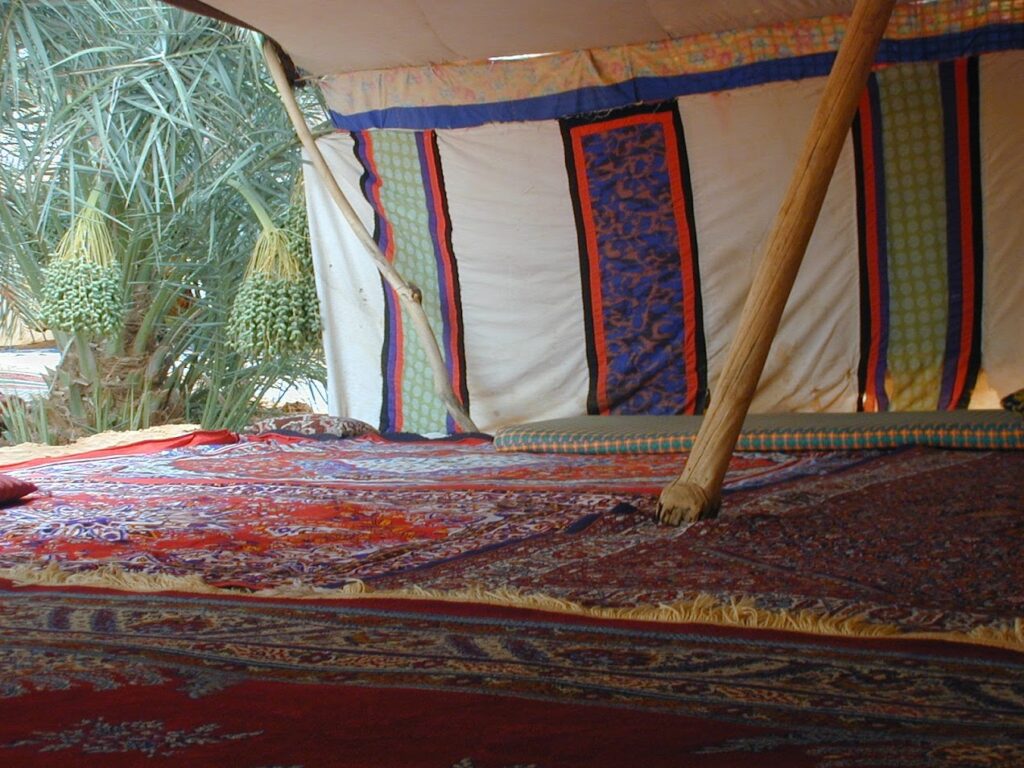 Cozy tent interior with patterned fabrics and a wooden support pole.