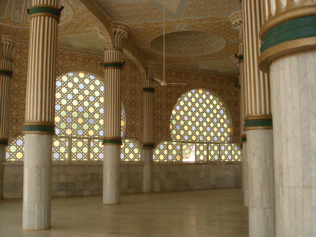 Interior view of an ornate mosque with arched windows and columns.