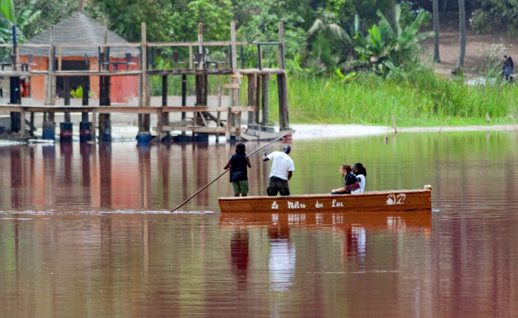 People on a boat in a flooded area surrounded by trees.