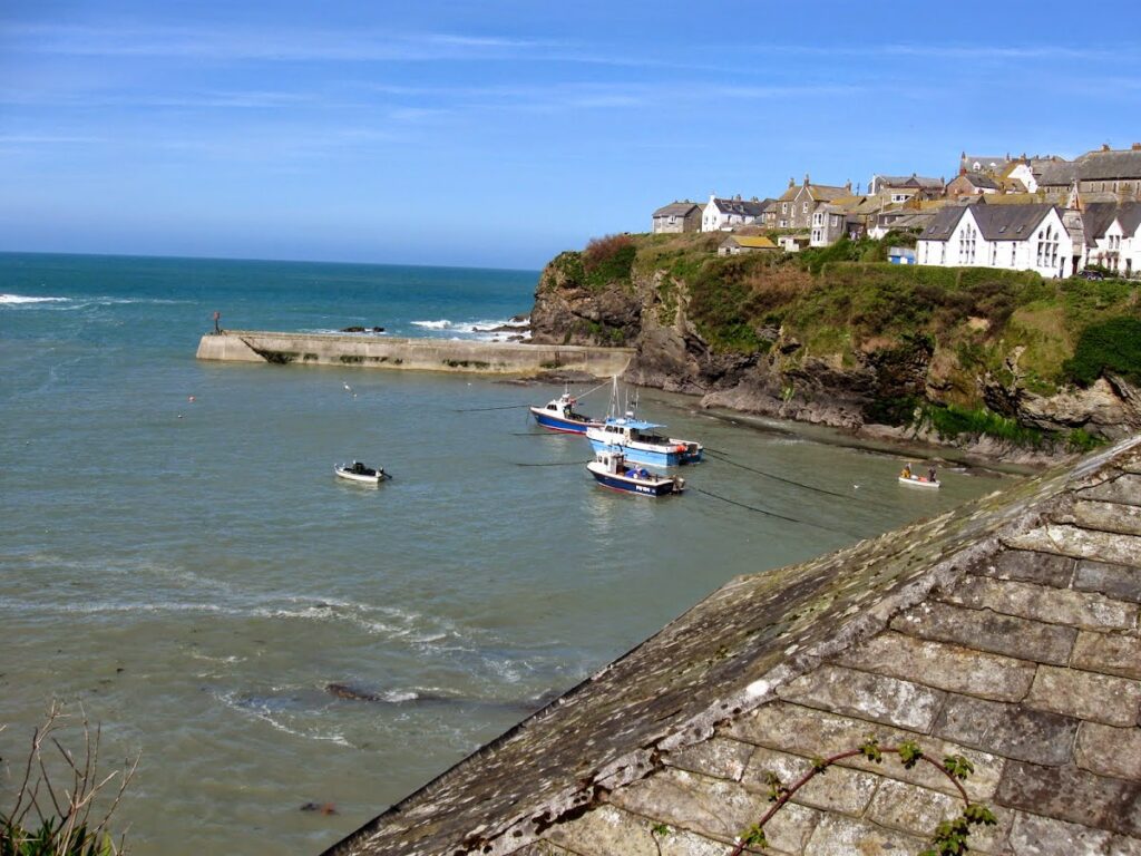 Small boats anchored near a rocky seaside village under a clear blue sky.