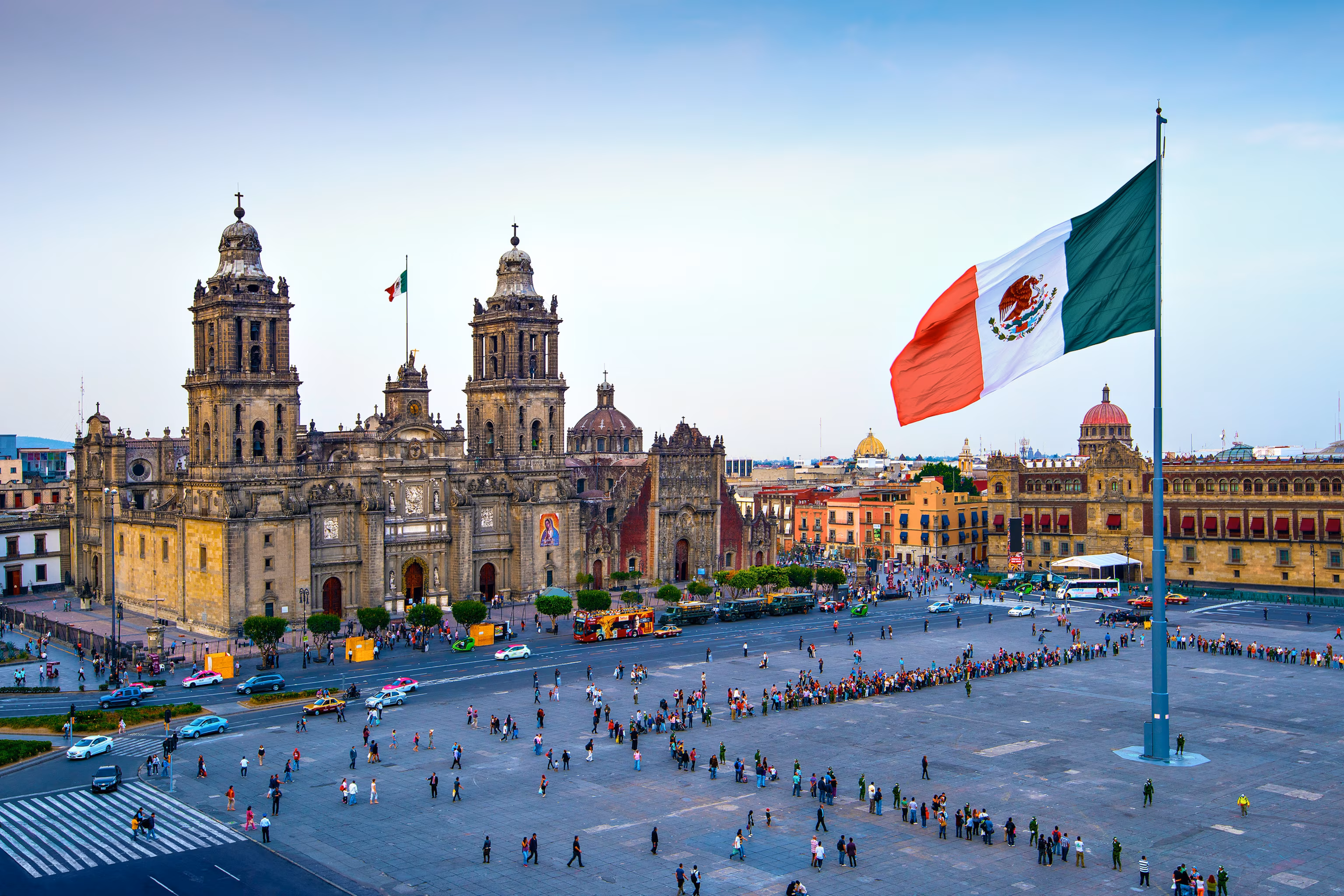 A panoramic view of Mexico City's historic Zócalo plaza with the Mexican flag flying.