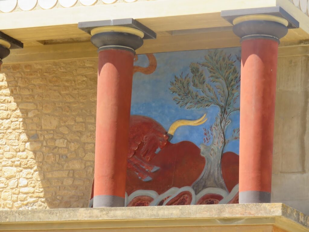 Ancient fresco of a red bull behind columns at a historic site.