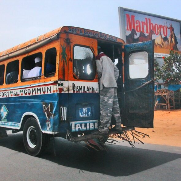 A colorful bus with passengers boarding in a sunny setting.