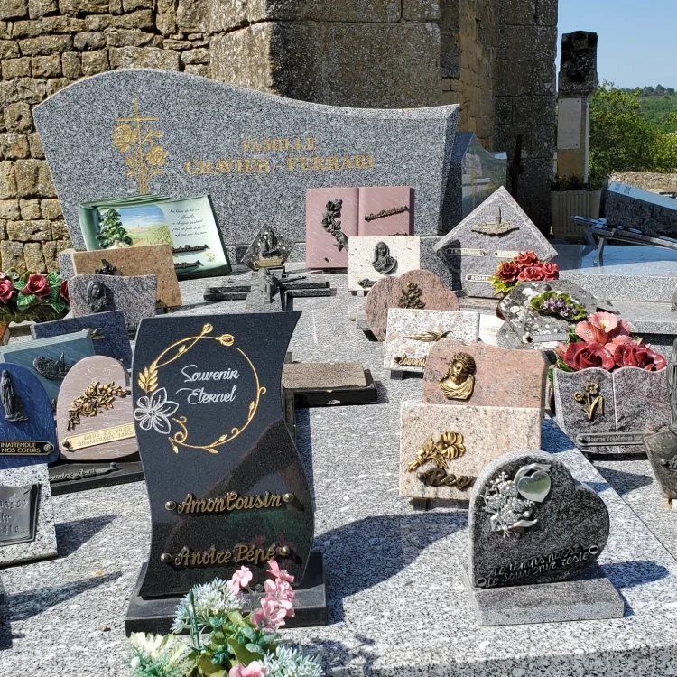 A variety of gravestones with flowers and memorial plaques in a cemetery.