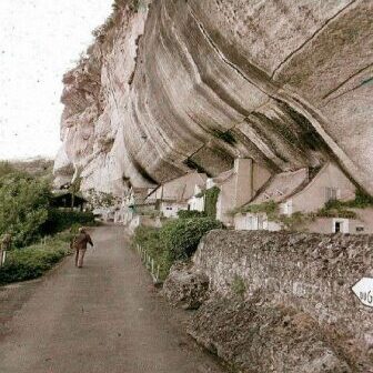A person walking near a large rock formation with carved niches.