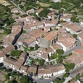 Aerial view of a historic village with stone buildings and red-tiled roofs.