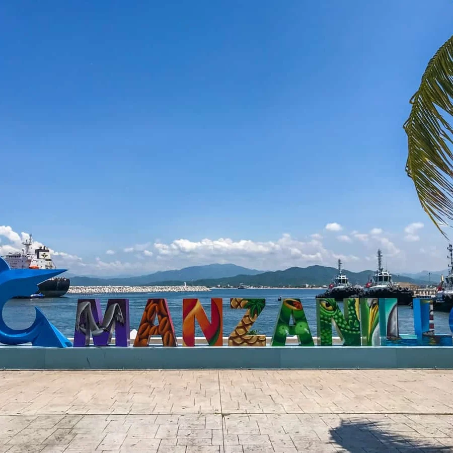Colorful MANZANILLO sign by the waterfront with clear blue sky.