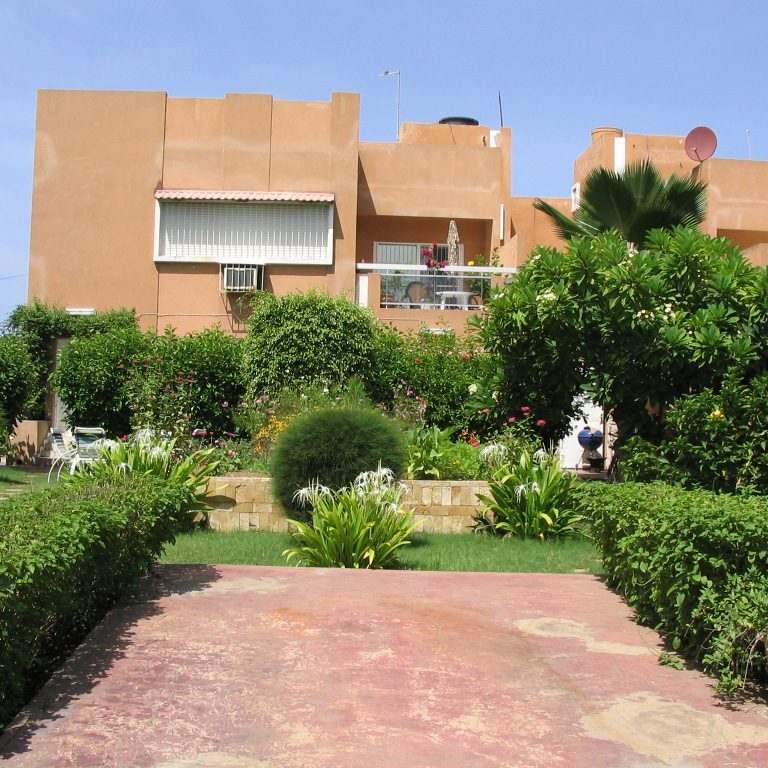 Orange building with greenery and a walkway in front.