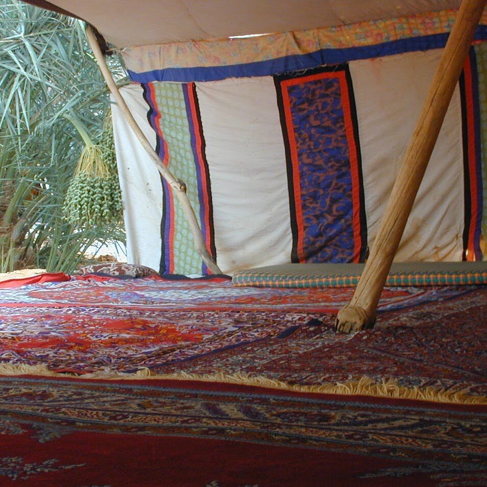 Cozy tent interior with patterned fabrics and a wooden support pole.