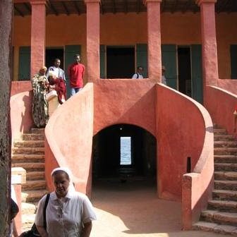 People exploring a historic red sandstone building with curved stairs.