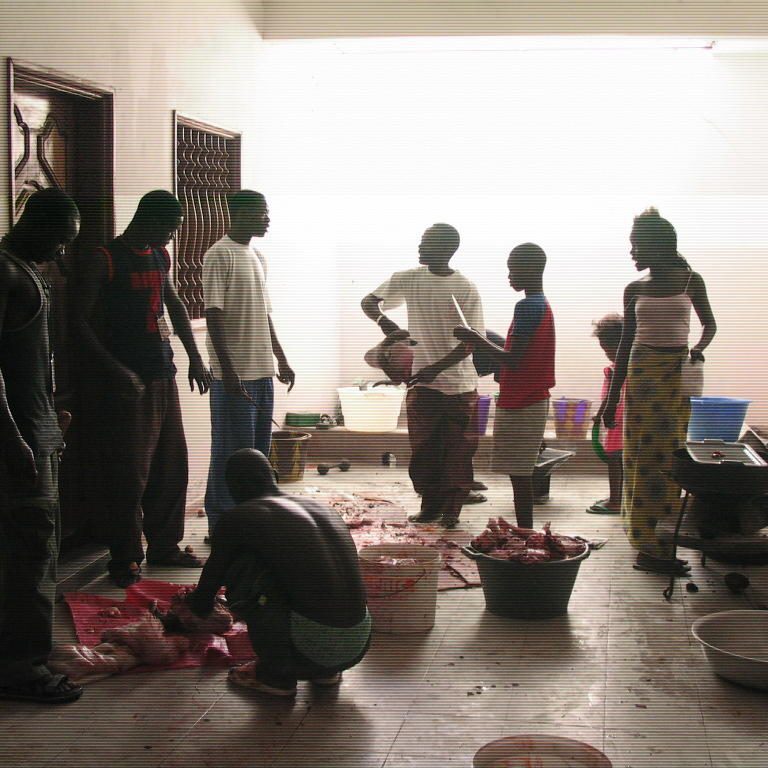 People gathered indoors, some sitting and some standing, in a dimly lit room.