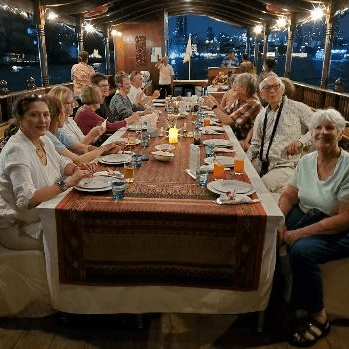Group of people dining together at a long table in a cozy restaurant.