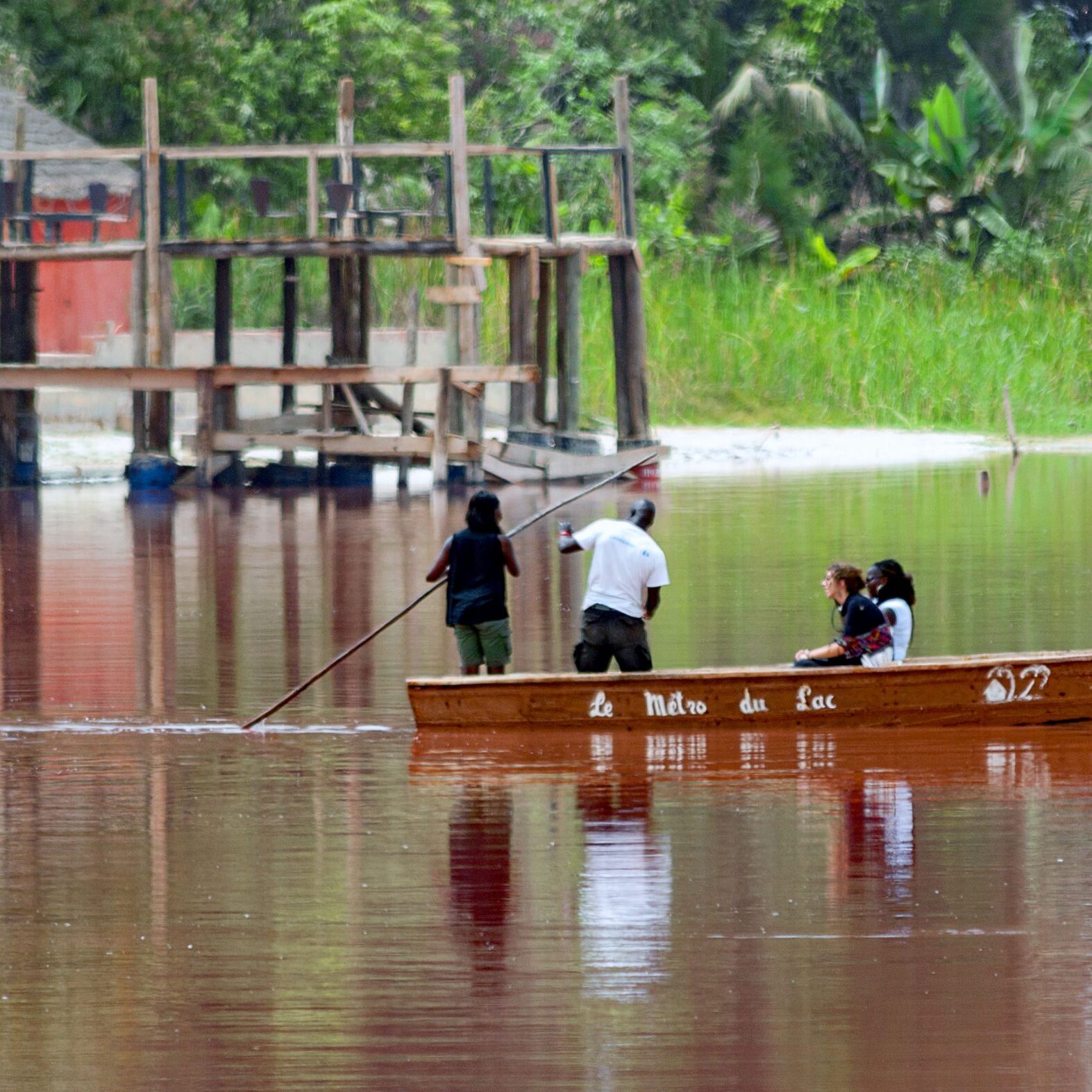 People on a boat in a flooded area surrounded by trees.