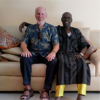 Two men sitting on a couch, smiling warmly.