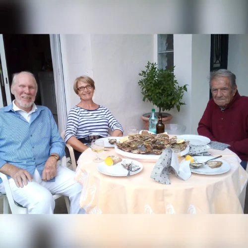 Three elderly people sitting at a dining table enjoying a meal together.